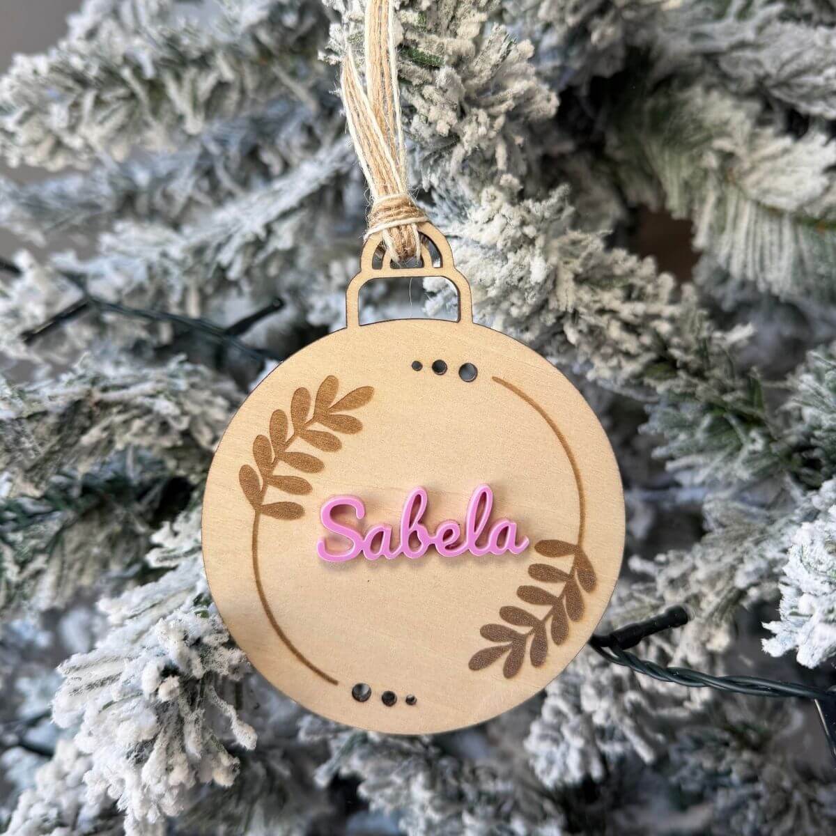 Bola de Navidad personalizada con nombre en metacrilato de color. Adorno para árbol de Navidad con hojas grabadas y nombre personalizado. Bola navideña personalizada con nombre de metacrilato. Decoración de Navidad para el árbol con nombre y diseño de hojas. Bola de Navidad con hojas grabadas y nombre en color. Adorno navideño personalizado para regalar a la familia.